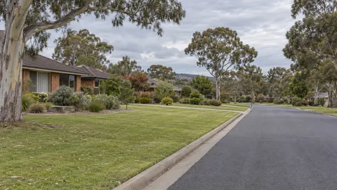 Wide suburban street with grass verge, eucalyptus trees and brick homes