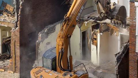 Excavator demolishing an older suburban house on a residential block