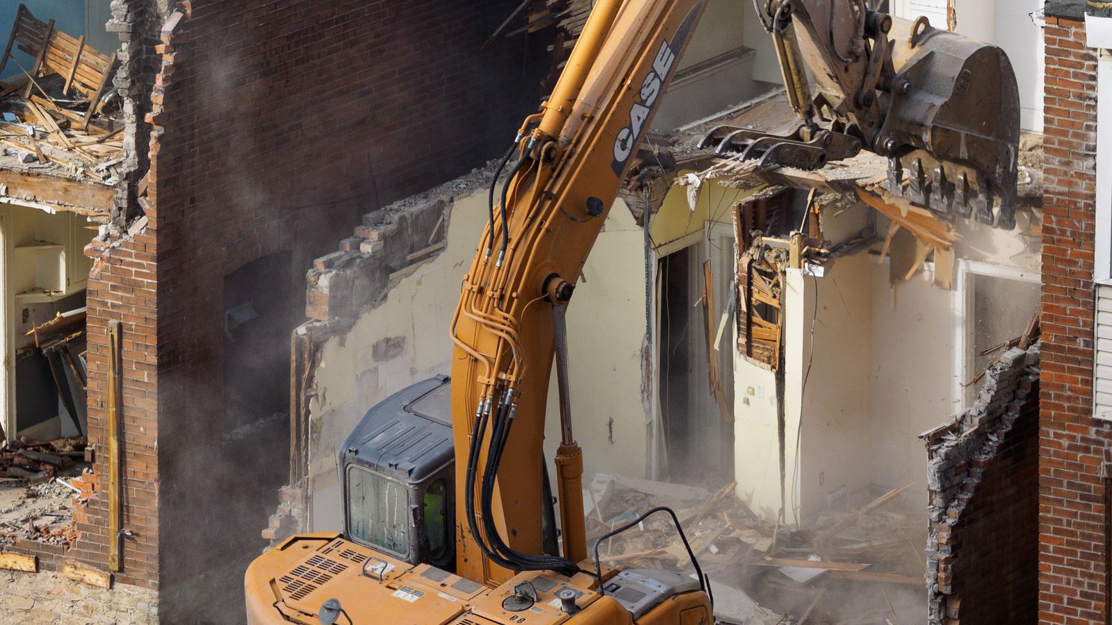 Excavator demolishing an older suburban house on a residential block