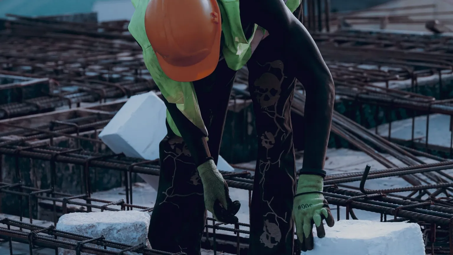 Construction worker in safety gear placing a concrete block on site, used to illustrate pre-start construction risk