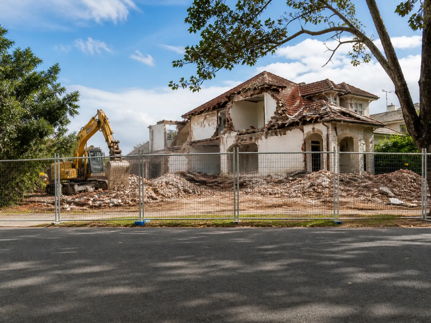 Excavator demolishing an old house on a residential block