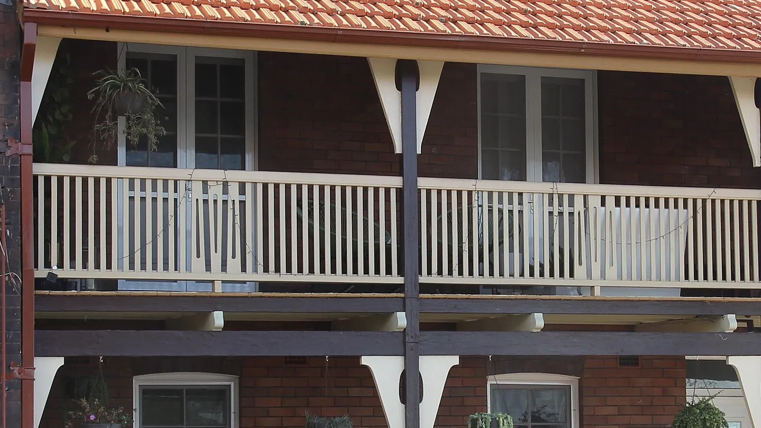 Two-storey brick terraces with lace-trimmed upper verandahs and tiled roofs on an inner Sydney street