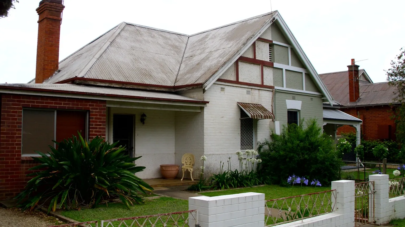 Two attached dwellings sharing a frontage, with rendered and brick walls, a tiled roof and a shared low front fence on a New South Wales street