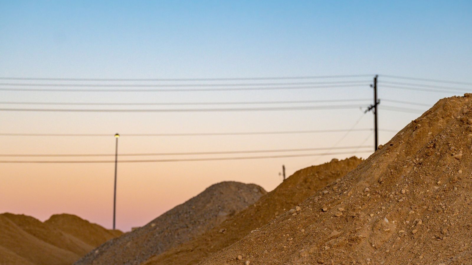 Mounds of excavated soil stockpiled beside utility poles