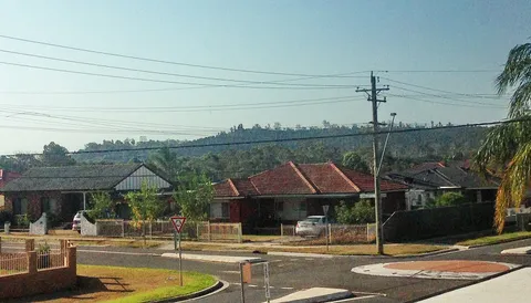 Completed brick and tile houses along a suburban street with established street trees.
