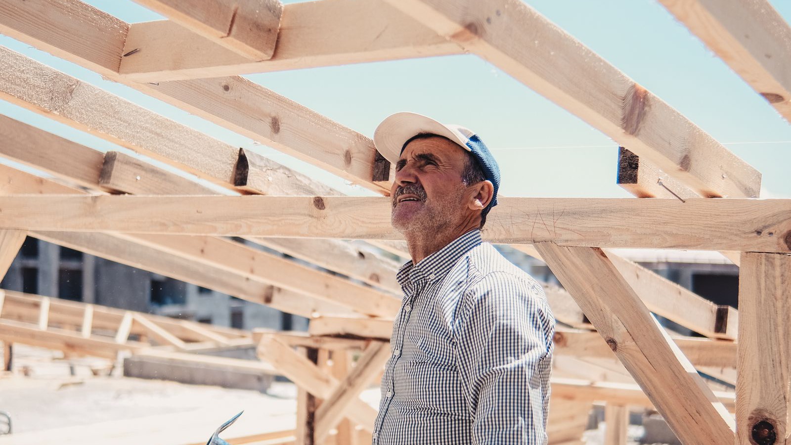 Person in a cap beneath exposed timber house framing