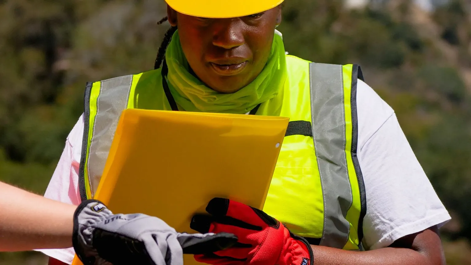 Construction manager updating project costs beside building plans