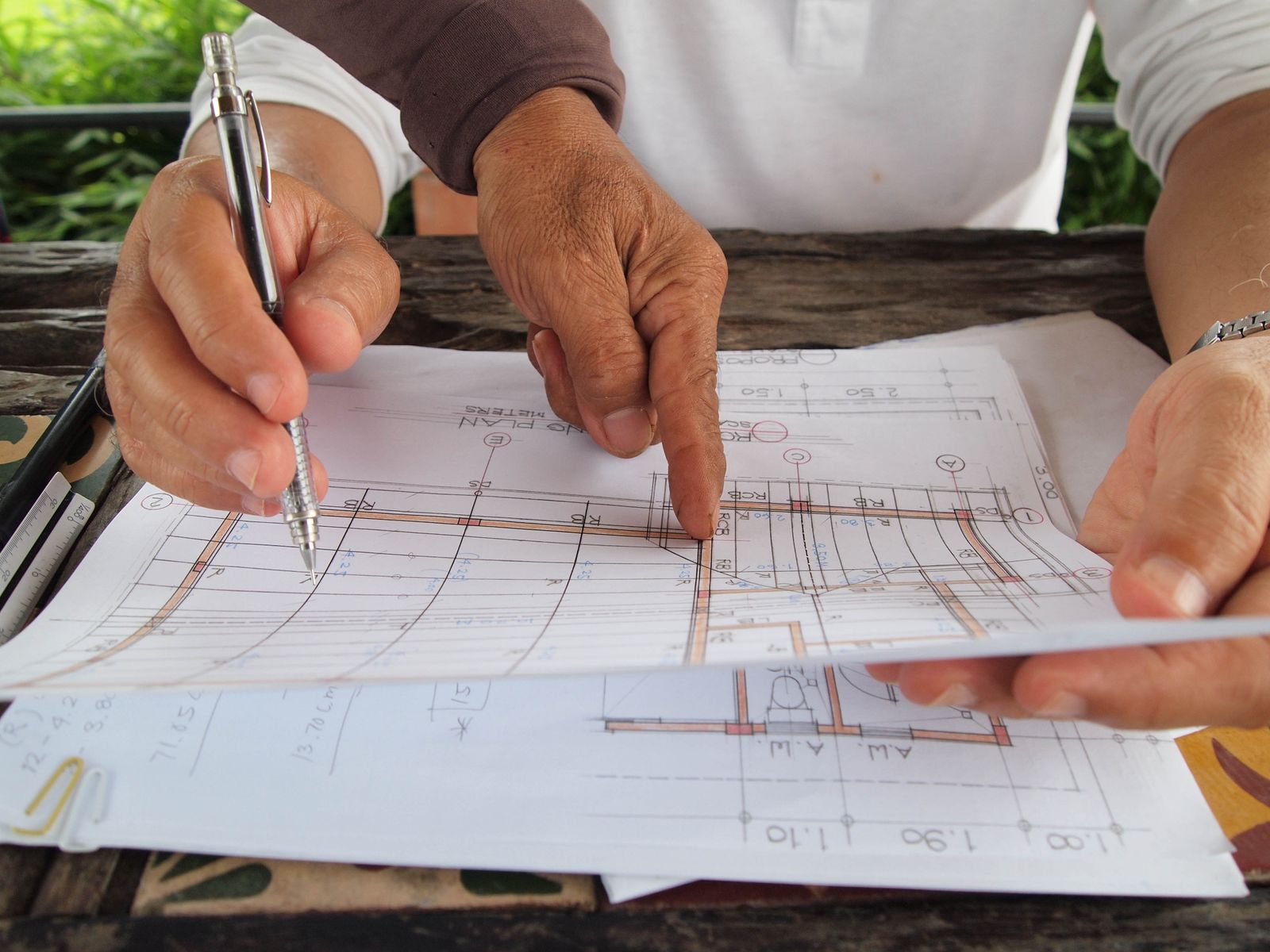 Hands reviewing construction drawings and project assumptions