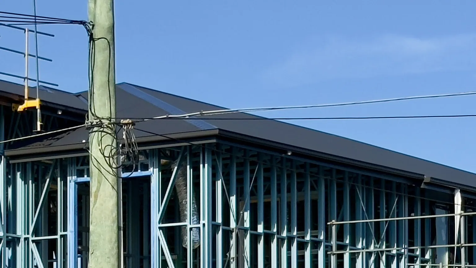 A steel-framed Queensland building under construction, with wall framing and roof structure visible.