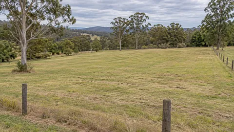 Open mown pasture with post and wire fencing on a rural-residential lot